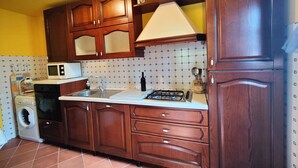 A kitchen with wooden cabinets, a microwave, a sink, a stove, and a washing machine. - Detached house in nature suitable for families (2 double bedrooms) and dogs (Camaiore)