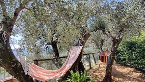 A hammock tied between trees in a garden area with a pathway and a potted plant. - Detached house in nature suitable for families (2 double bedrooms) and dogs (Camaiore)