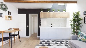 Una cocina moderna con armarios blancos, salpicadero negro y techo de madera.