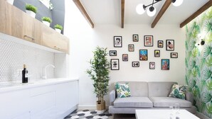 Una cocina moderna con encimera blanca, suelo de patrón hexagonal y un sofá gris con cojines decorativos.
