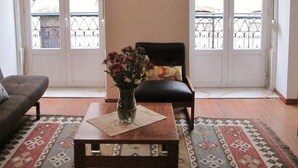 A living room with a sofa, a coffee table with a vase of flowers, a chair, and a painting on the wall.