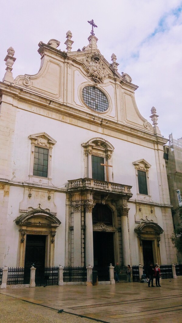 A historic building with ornate architectural details, including a prominent central dome, multiple windows with shutters, and a gated entrance.