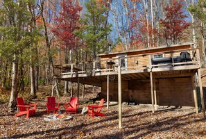 A cabin with a deck, outdoor seating, and a fire pit. - Cozy Cabin w Lake, Hot Tub, Huge Deck & Fire Pit (Mathias)