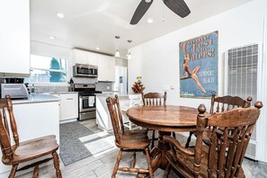 A modern kitchen with white cabinets, stainless steel appliances, and a dining area with a wooden table and chairs.