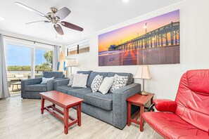 A living room with a grey sofa, red leather chair, wooden coffee table, and a ceiling fan. - Enjoy Amazing Views of the Harbor, From the Coolest Patio in Town! (Newport Beach)