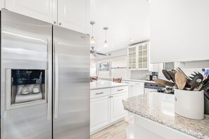 A modern kitchen with white cabinetry, a stainless steel refrigerator, a built-in coffee maker, and a knife block on the countertop. - Enjoy Amazing Views of the Harbor, From the Coolest Patio in Town! (Newport Beach)