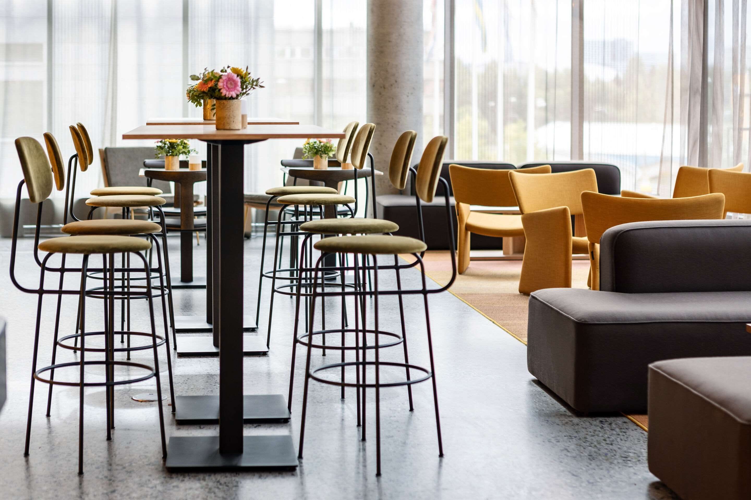 A modern interior with a central table surrounded by chairs, a sofa, and a bar area.