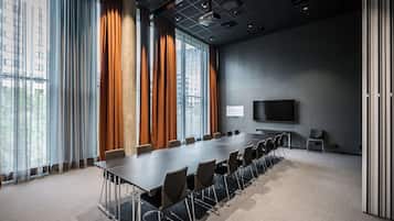 Uma sala de conferências com uma mesa comprida, cadeiras, um projetor e uma tela de televisão.