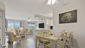 Een ruime woonkamer met een eethoek, een keuken en een groot raam met uitzicht op de omgeving.