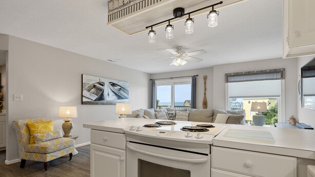 Een moderne keuken met een centraal eiland, witte kasten en een plafondventilator.