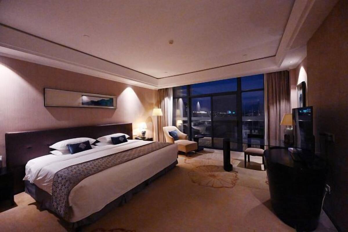 A hotel room with a large bed, a chair, a desk, and a TV.