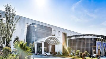 Um edifício moderno com fachada de vidro, entrada coberta e seção circular com design azul e dourado.
