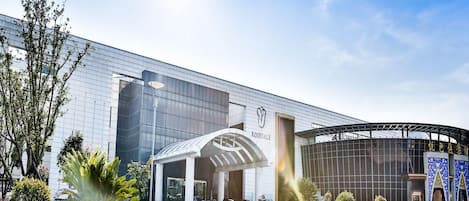 A modern building with a glass facade, a covered entrance, and a circular section with a blue and gold design.