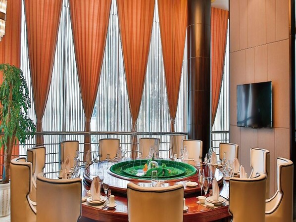 A dining area with a round table set for six, surrounded by chairs, with a large window and curtains in the background. - Jiuhua Chunshenhu Suzhou (Suzhou)