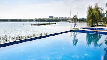 Piscina infinita com vista desimpedida para uma ponte e paisagem urbana ao fundo.