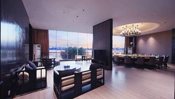 A spacious living area with a large window, a dining table, and a pool table.