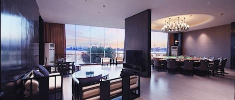 A spacious living area with a large window, a dining table, and a pool table.