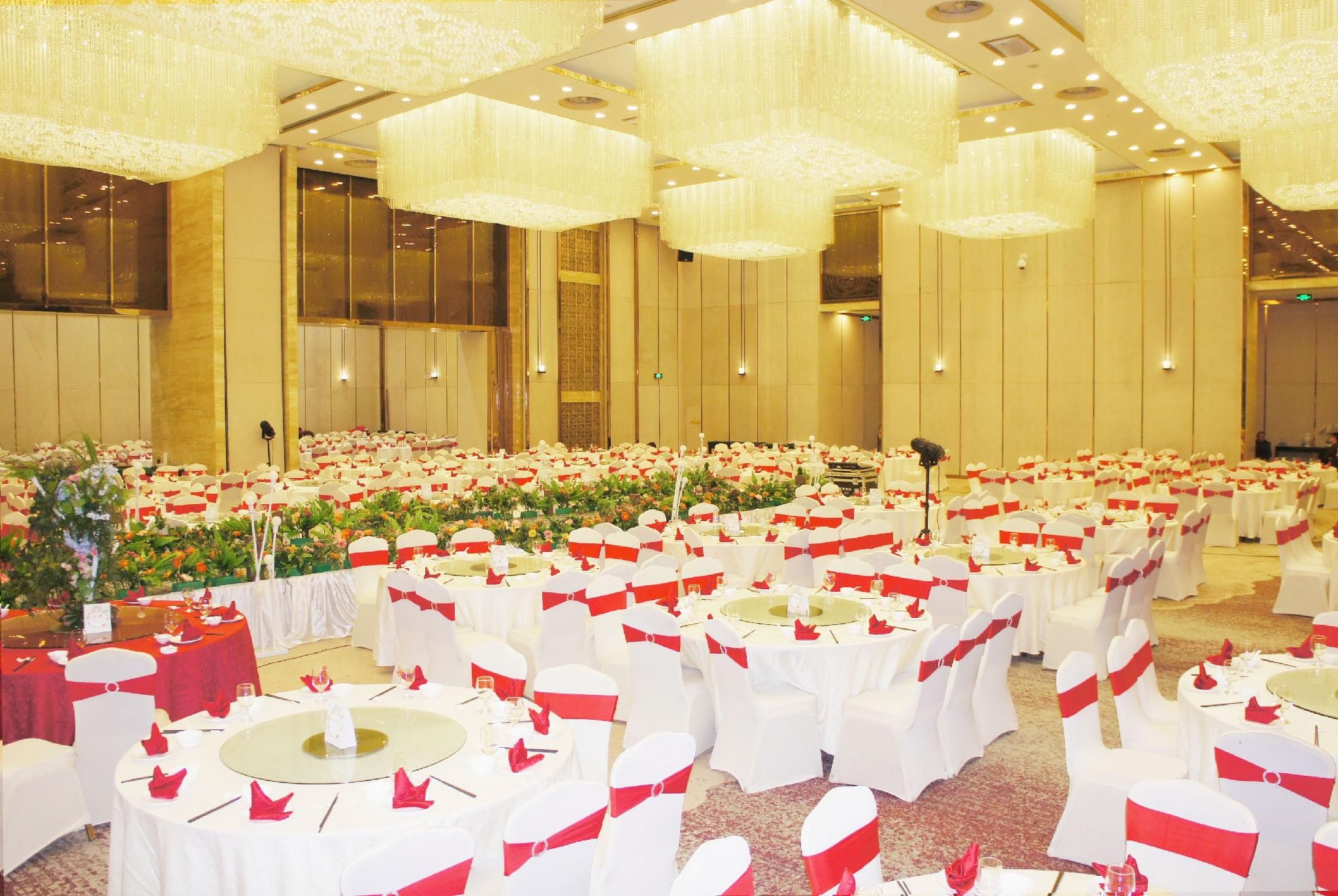 A banquet hall with round tables, white tablecloths, and red sashes.