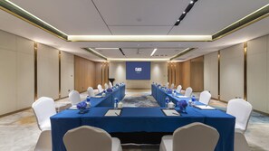 A conference room with a long table, white chairs, and a projector screen. - Holiday Inn Express E'mei Qiliping (Leshan)