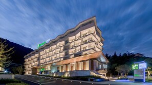 Een modern Holiday Inn Express hotel met een opvallend architectuur, met meerdere balkons en een goed verlichte ingang.