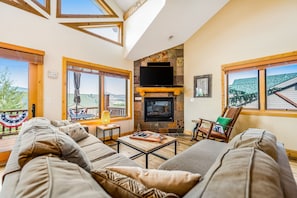 Relax in this spacious living room with a high ceiling, large windows, and a cozy seating area.