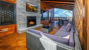 A cozy living area with a stone fireplace, wicker furniture, and a view of the outdoors.
