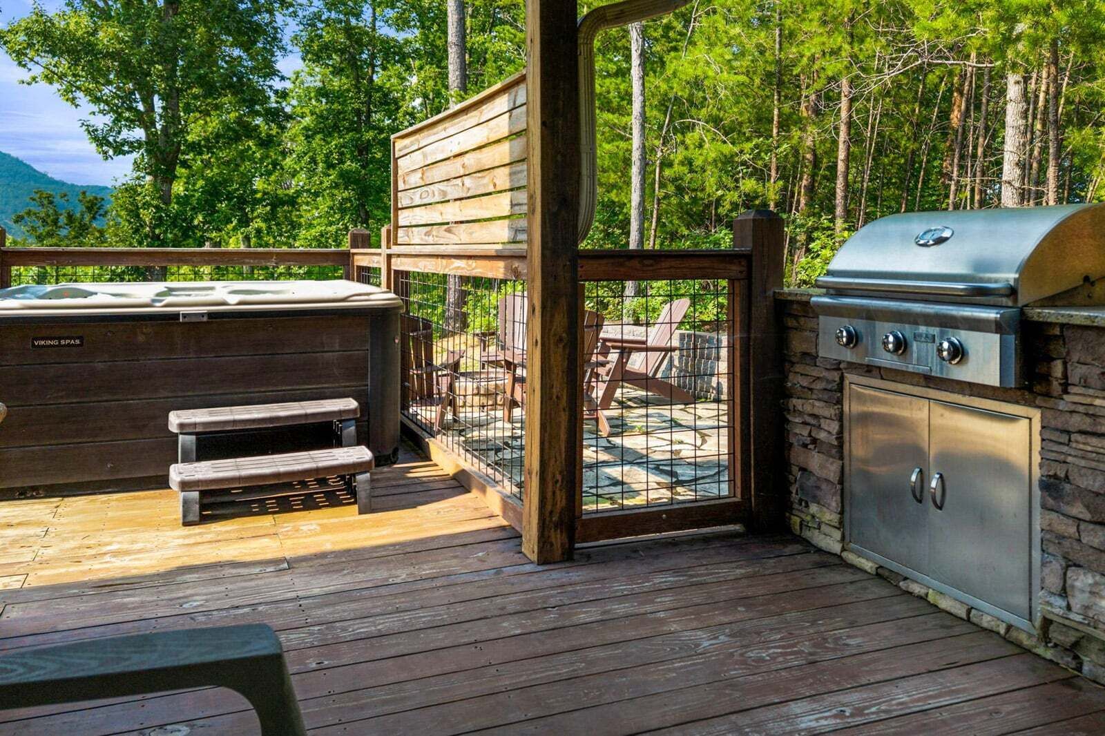 An outdoor deck with a hot tub, barbecue grill, and wooden benches.