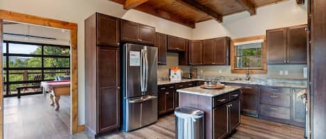 A modern kitchen with wooden cabinets, a stainless steel refrigerator, and a large island with a sink.