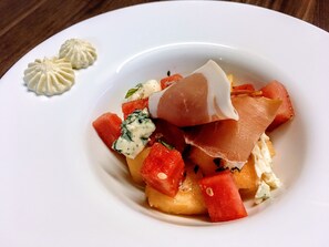 Ein Teller mit einem Gericht aus Wassermelone, Käse und einem Gebäckstück.