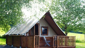 Een houten chalet met schuin dak, een terras en een raam.