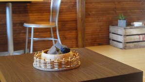 Een houten tafel met een gevlochten mand waarin een steen en een kandelaar liggen.