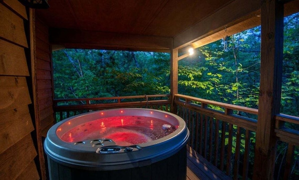 Relax in a hot tub on the elevated deck, surrounded by lush greenery.