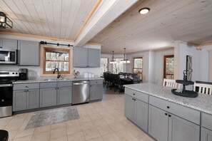 Enjoy cooking in this well-equipped kitchen with a spacious layout, grey cabinetry, and a stainless steel dishwasher.