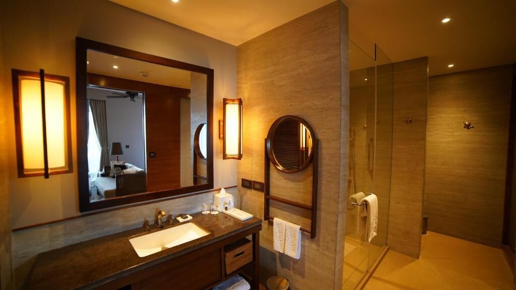 A modern bathroom with a large mirror, a vanity with a sink, a shower area, and a towel rack.