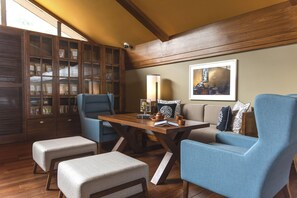 A room with a wooden ceiling, a dining table with chairs, a sofa, a cabinet with glass doors, and a framed picture on the wall. - Taj Chia Kutir, Resort & Spa (Kurseong)