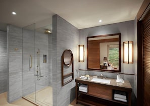 A modern bathroom with a glass-enclosed shower, a wooden vanity with a sink, and a large mirror.