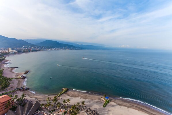 A coastal view with a beach, a marina, and a cityscape in the background. - Stunning bay views beachfront 25th floor condo (Puerto Vallarta)