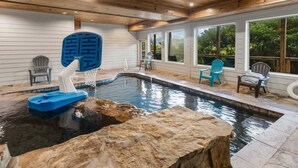 Una piscina con aro de baloncesto, sillas Adirondack y techo de madera.