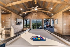 A wooden interior with a pool table, ceiling fan, and large windows. - Splash 'N Heavenly Views – Indoor Pool, Theater & Mountain Views (Gatlinburg)