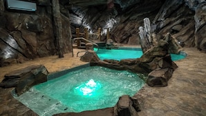 Ein Wellnessbereich mit Pool, Felsformationen und einem hölzernen Gang.