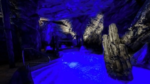 Ein Innenraum, der einer Höhle ähnelt, mit einem Pool, Bänken und einer großen Felsformation.