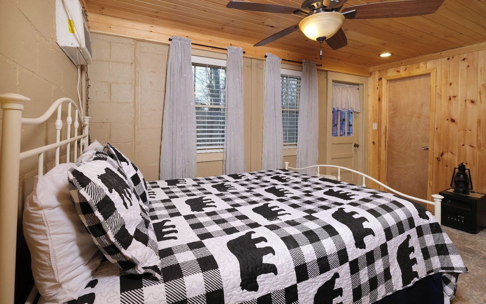 A bedroom with a bed, a ceiling fan, and a window with curtains.