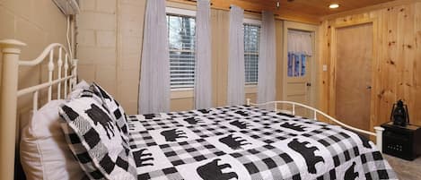 A bedroom with a bed, a ceiling fan, and a window with curtains.