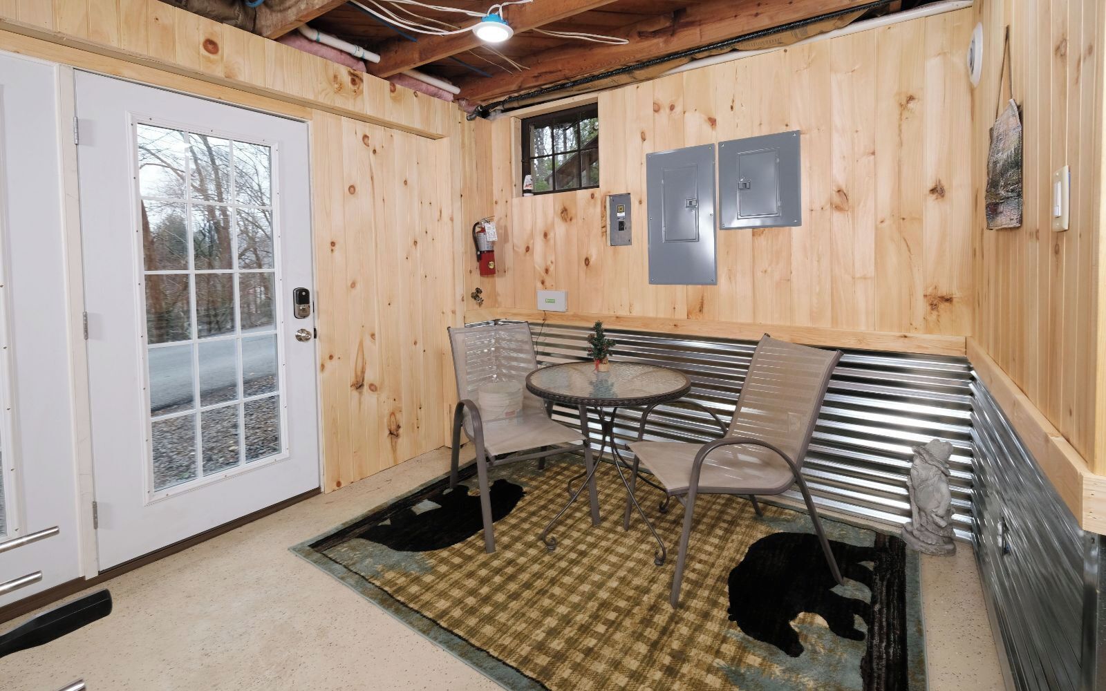 Un interior de madera con una puerta, una pequeña mesa con sillas y un extintor.
