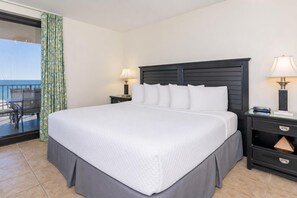 Habitación de hotel con una cama grande, dos mesitas de noche con lámparas, un balcón con vistas y una puerta corrediza con cortinas.