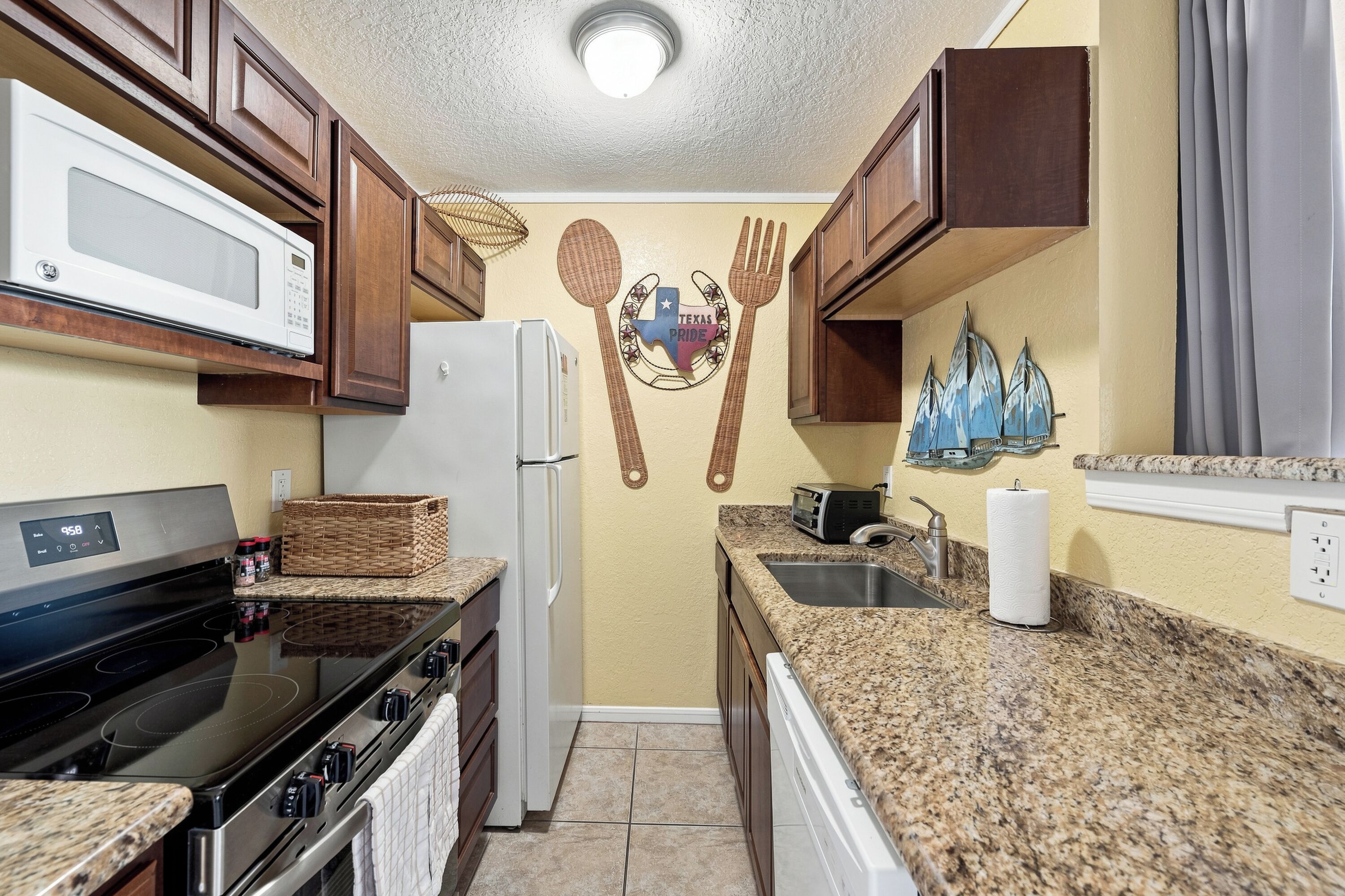 A kitchen with a microwave, stove, refrigerator, and granite countertops.