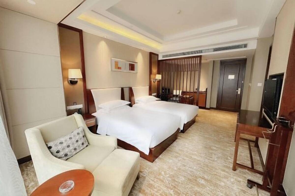 A hotel room with a large bed, a sofa, a small table, and a TV.