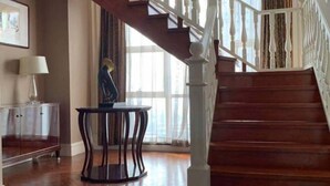 A wooden staircase with white balusters, a clear glass cabinet, and a small round table with a lamp. - Zhongwei International Holiday Hotel (Fushun)