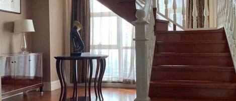 A wooden staircase with white balusters, a clear glass cabinet, and a small round table with a lamp.