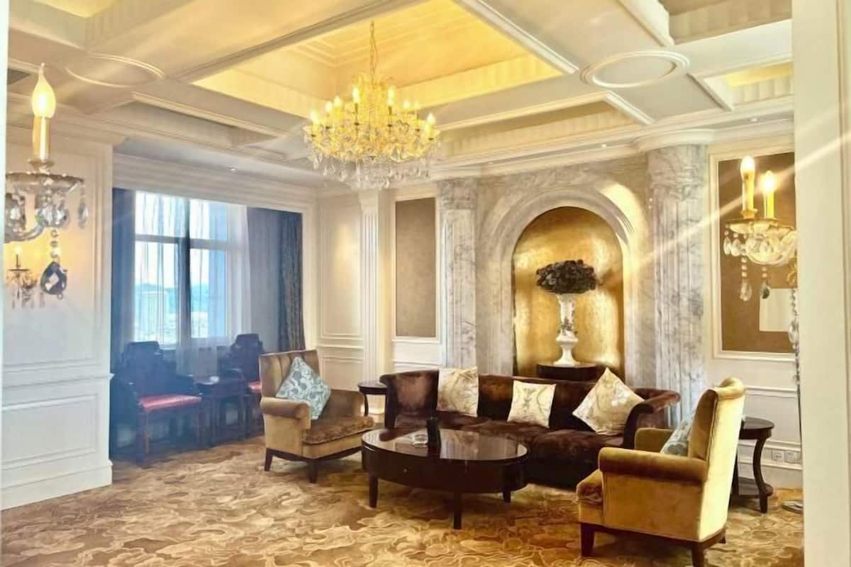 A luxurious living room with a grand chandelier, comfortable seating, and a fireplace.